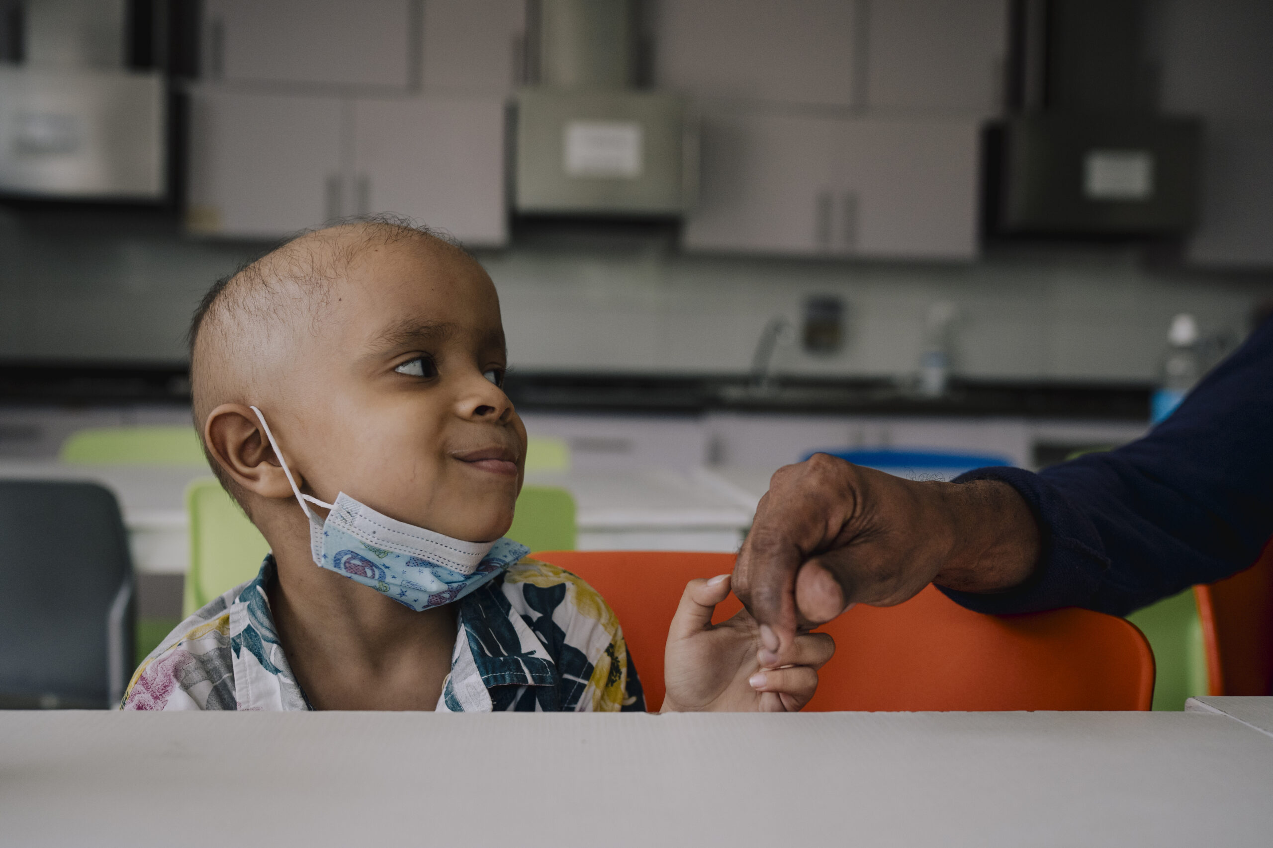 Child hold a hand and smiling up to the person